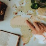 A person pointing at a map with a globe and a plant