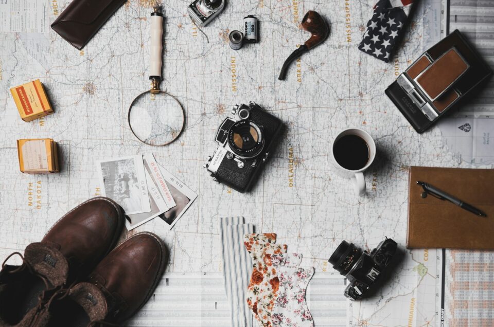 camera, pair of brown shoes, white ceramic mug, grey and black pen, brown smoking pipe